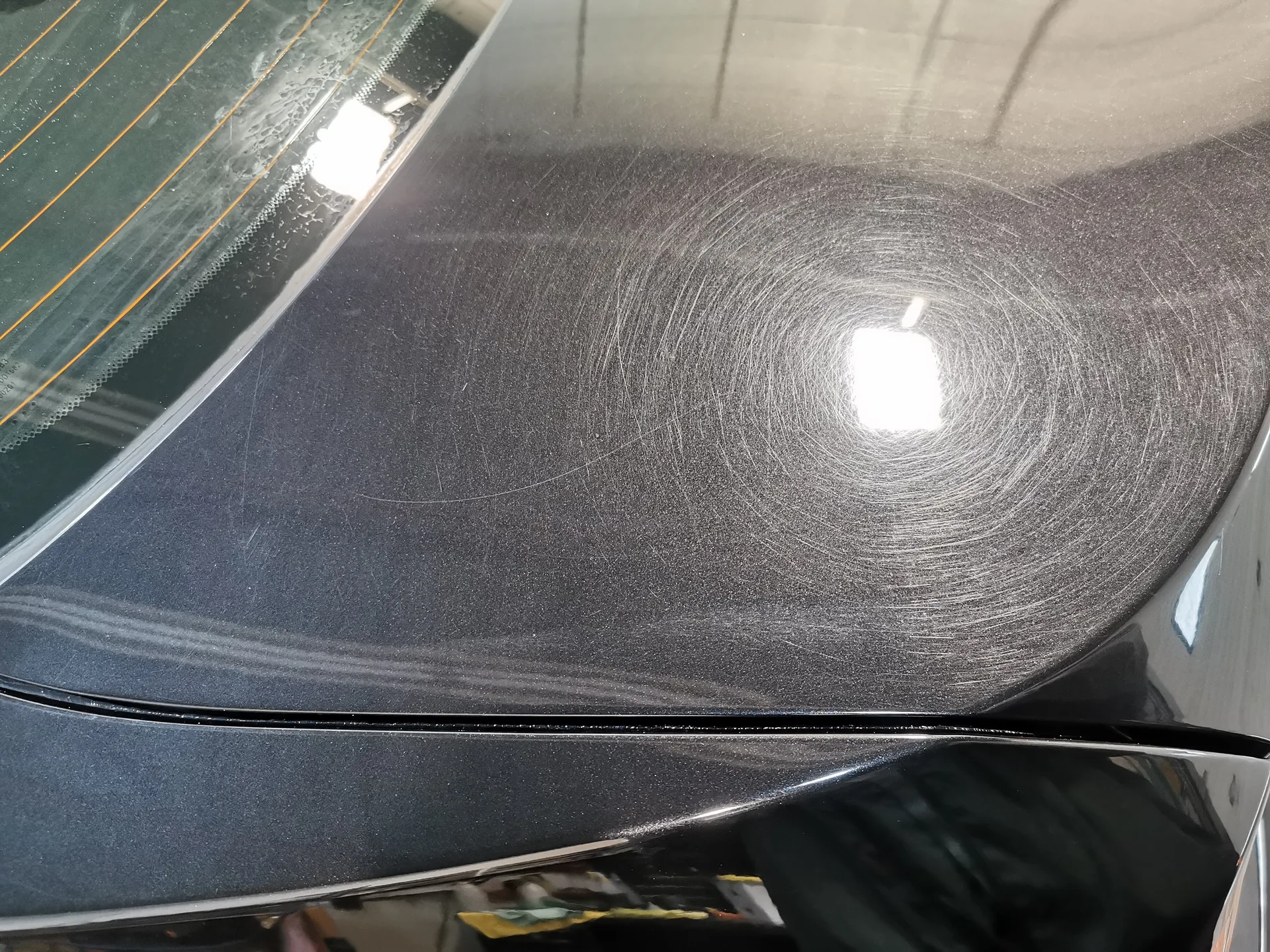 Close-up of swirl marks and sanding hologram pattern on dark metallic paint before paint correction at Ultimate Detail Bowmanville